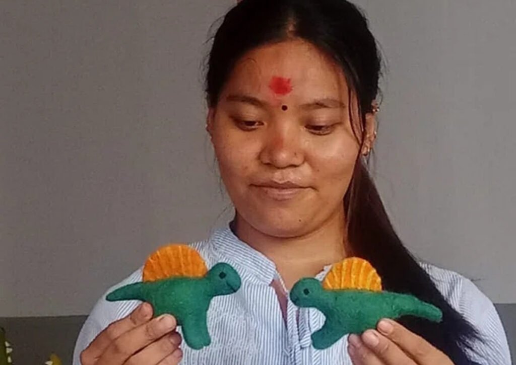 Woman holding handmade felted dinosaur toys - Hillyarn custom wool design