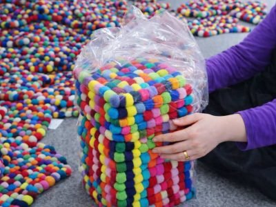 Bulk packaging and global shipping of handmade felt ball rugs from Nepal, international wholesale logistics via DHL, FedEx, UPS, Aramex, and TNT.